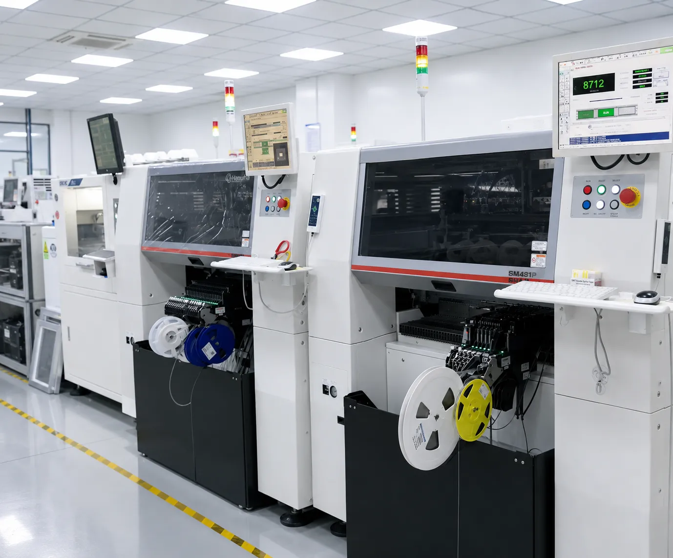 Several Hanwha SM481P placement machines standing in a row in a cleanroom production line with tape reels loaded