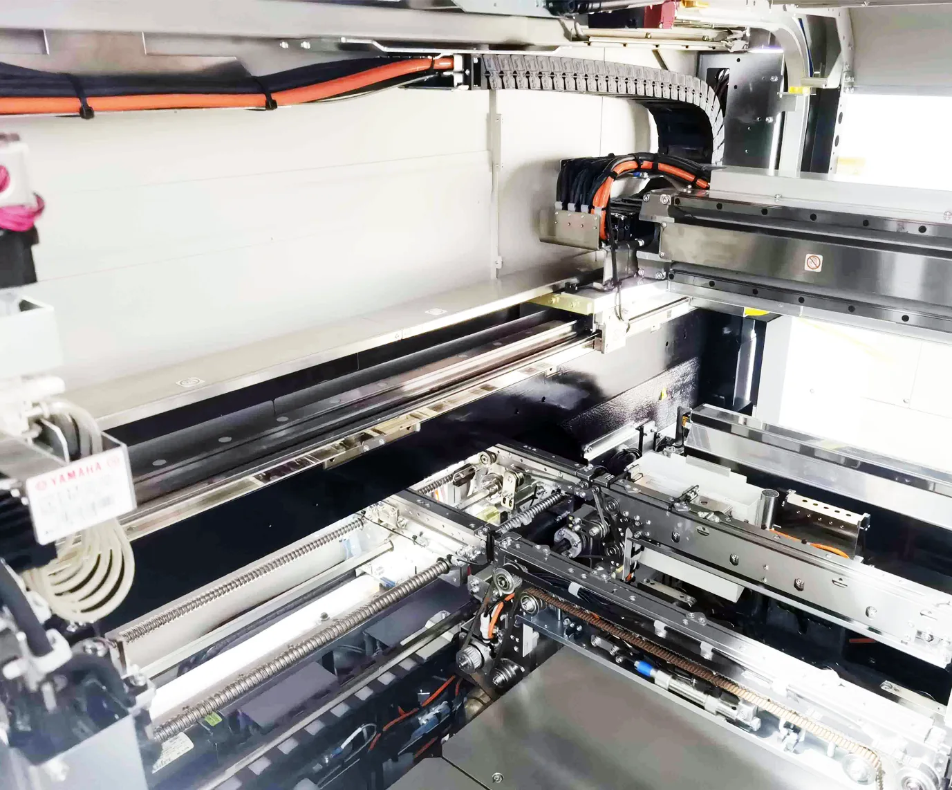 Detail view of the conveyor and rail system inside a Yamaha mounter, with the YAMAHA label on the frame